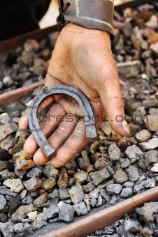 Detail of dirty hand holding horseshoe - blacksmith