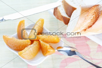 Baguette on plate, peach dessert, spoon and knife