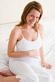 Pregnant woman sitting in bed smiling