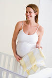 Pregnant woman setting up baby crib smiling