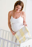 Pregnant woman setting up baby crib smiling