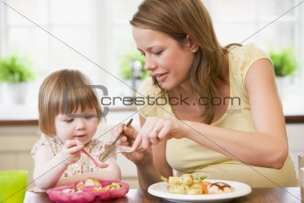 Pregnant mother in kitchen eating chicken and vegetables helping