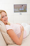 Pregnant woman watching television smiling