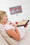 Pregnant woman watching television and eating chocolates smiling