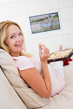 Pregnant woman watching television and eating chocolates smiling