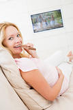 Pregnant woman watching television and eating chocolate smiling