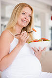 Pregnant woman with bowl of salad smiling