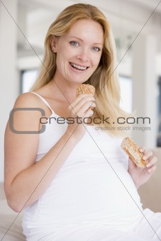 Pregnant woman eating bread and smiling