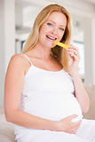 Pregnant woman eating melon slice and smiling