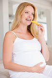Pregnant woman eating melon slice and smiling