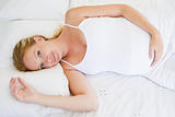 Pregnant woman lying in bed smiling