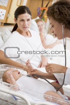 Doctor checking baby's heartbeat with new mother watching