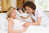Nurse checking pregnant woman's belly and smiling