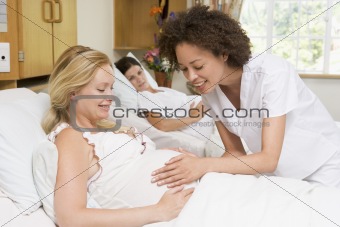 Nurse checking pregnant woman's belly and smiling