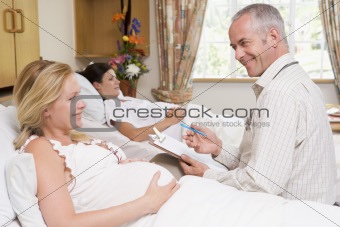 Doctor talking to pregnant woman holding chart and smiling