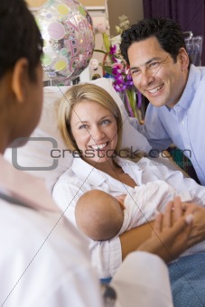 New parents with baby talking to doctor and smiling