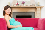 Pregnant woman sitting in living room smiling