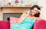 Pregnant woman in living room talking on telephone and smiling