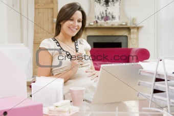 Pregnant woman in home office with laptop eating and smiling