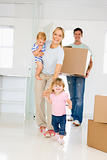 Family with box moving into new home smiling