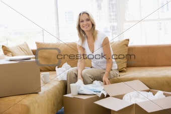 Woman unpacking boxes in new home smiling