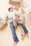 Couple lying on floor by open boxes in new home smiling