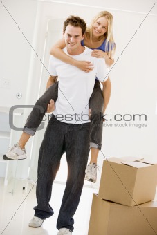 Husband giving wife piggyback in new home smiling
