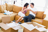 Couple relaxing with champagne by boxes in new home smiling