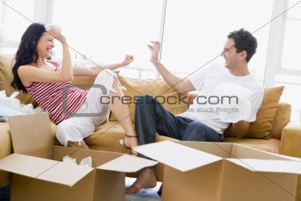 Couple playfully unpacking boxes in new home smiling