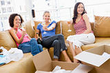 Three girl friends relaxing with champagne by boxes in new home 