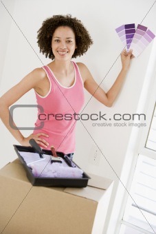 Woman with paint swatches in new home smiling