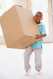 Young boy holding box in new home smiling