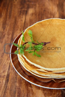 traditional American pancakes on a plate with a branch mint on a brown background
