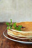 traditional American pancakes on a plate with a branch mint on a brown background