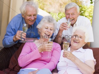 Two couples on patio drinking champagne and smiling