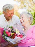 Husband giving wife flowers outdoors smiling