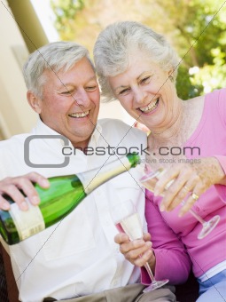 Couple on patio drinking champagne and smiling