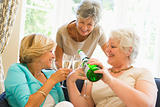 Three women in living room drinking champagne and smiling