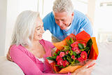 Husband giving wife flowers and smiling