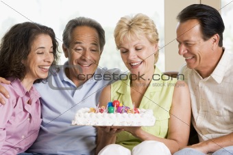 Two couples in living room with cake smiling