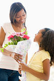 Mother giving daughter flowers and smiling