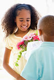 Young boy giving young girl flowers and smiling