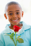 Young boy holding rose smiling