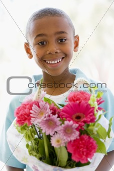 Young boy holding flowers smiling
