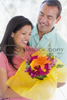 Husband and wife holding flowers and smiling