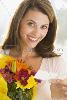 Woman holding flowers and note smiling