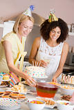 Two women at party setting out food smiling