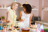 Two women at party standing by food table smiling