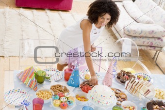 Woman at party fixing cake on food table smiling