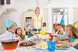 Young children at party sitting at table with mother carrying ca